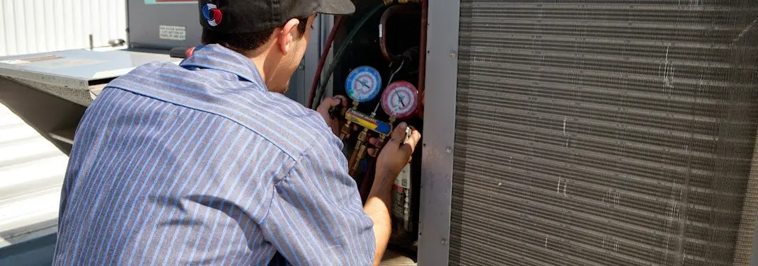 HVAC technician servicing a condenser unit in Aptos